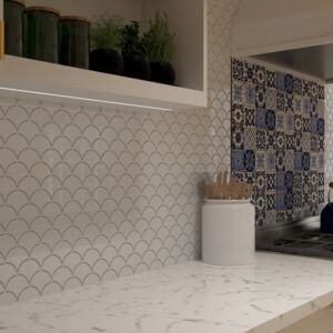 Cocina exótica con fregadero italiano | En esta imagen destaca el patchwork mexicano Azul Luz, que crea una impactante pared sobre la cocina. Estos azulejos de cerámica de México, pintados a mano y conocidos como azulejos Talavera, garantizan originalidad y autenticidad. Sus intensos patrones azules contrastan perfectamente con los muebles blancos y los elementos de madera, aportando a la cocina un carácter dinámico y vibrante. El conjunto se completa con la lámpara de cobre Aliso, que proporciona una iluminación cálida y acogedora.